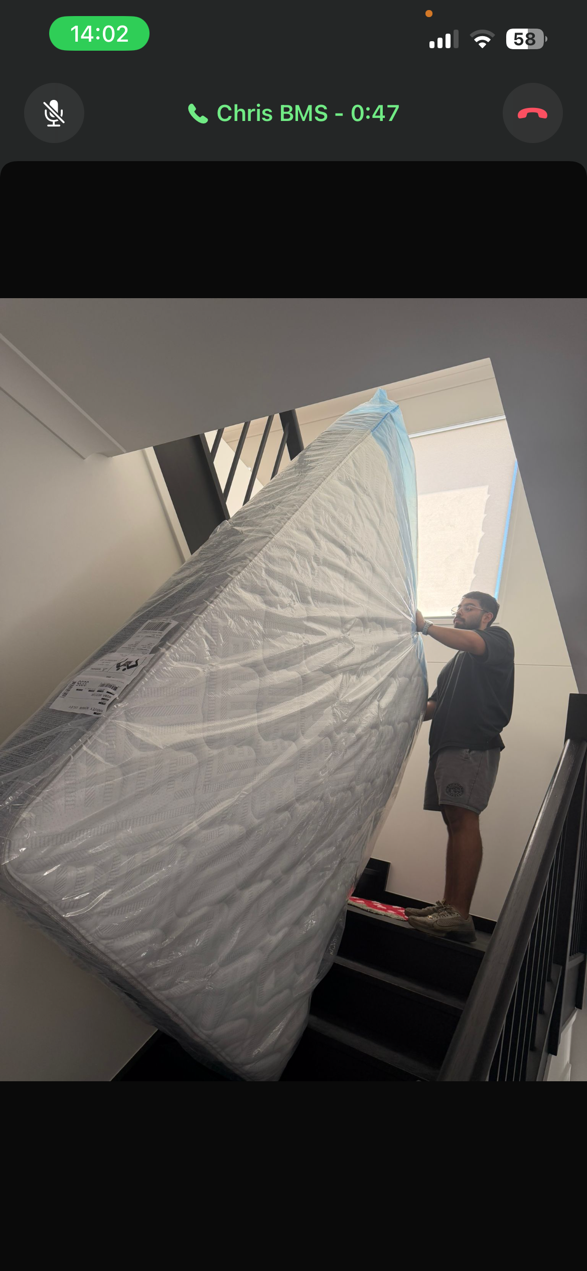 Team carrying mattress up staircase